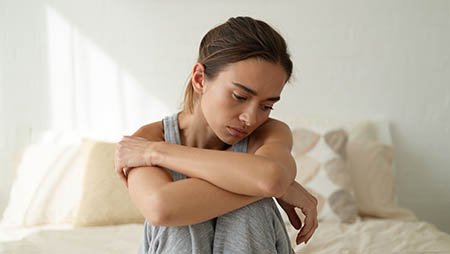 Девушка грустно обнимает колени